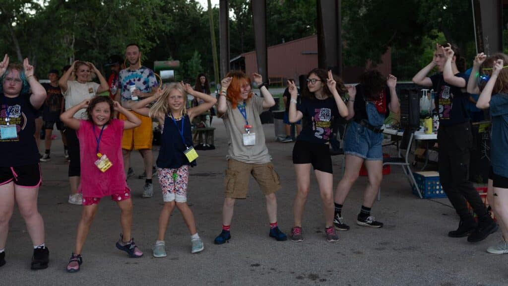 Group of campers standing side by side making silly faces and holding their hands up to their heads to form animal ears.